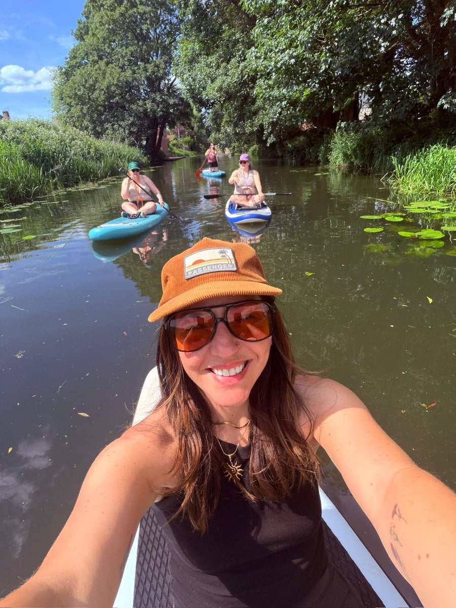 Woman paddleboarding on a river with her Grounded Connections group behind her
