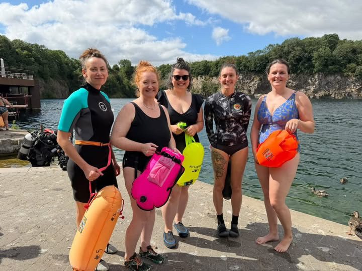 Group of women in wetsuits and swimsuits with tow floats before an open water swim