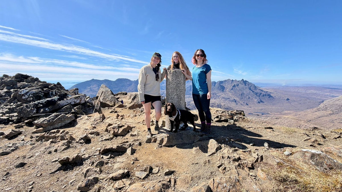 Women and a dog on a rocky mountain summit on a Grounded Connections hike